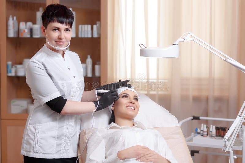 Cosmetologist som applicerar permanent smink på ögonbrynögonbryntatuering fotografering för bildbyråer Cosmetologist som applicerar permanent smink på ögonbrynögonbryntatuering fotografering för bildbyråer