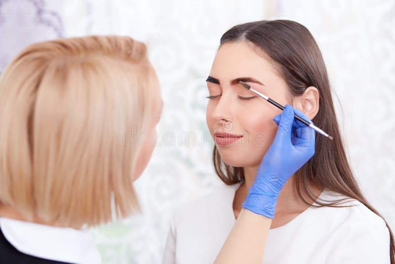 Cosmetologist στα γάντια που κάνει τα μόνιμα φρύδια για τη γυναίκα στοκ φωτογραφία με δικαίωμα ελεύθερης χρήσης Cosmetologist στα γάντια που κάνει τα μόνιμα φρύδια για τη γυναίκα στοκ φωτογραφία με δικαίωμα ελεύθερης χρήσης
