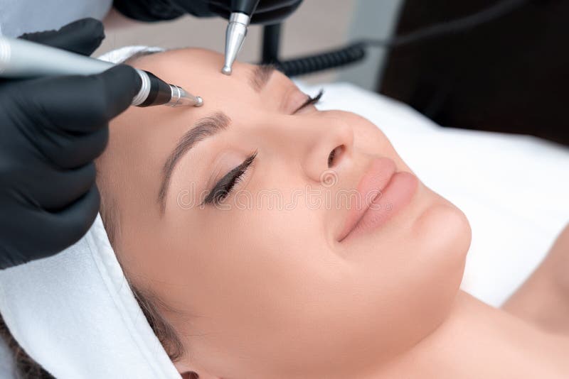 Cosmetology Beautiful Woman At Spa Clinic Receiving Stimulating Electric Facial Treatment From