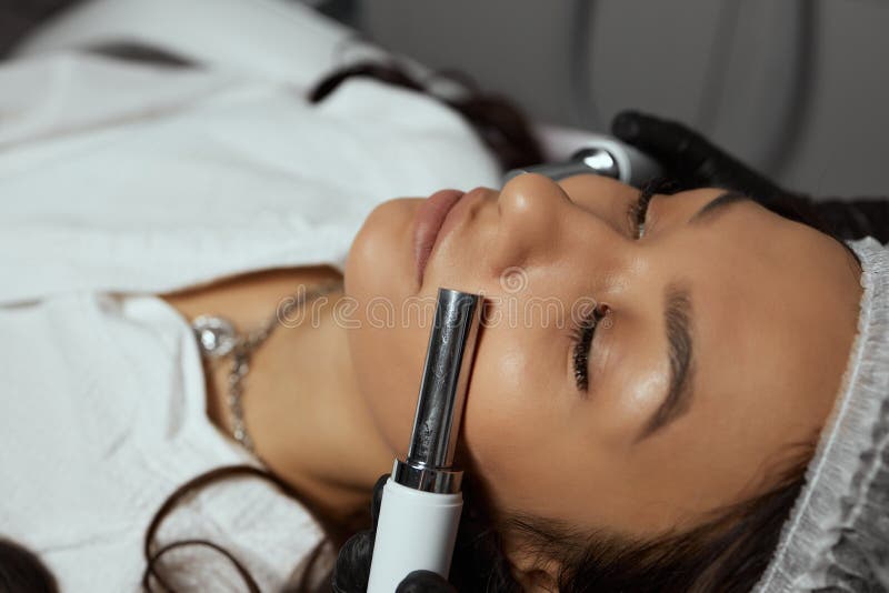 Cosmetology Beautiful Woman At Spa Clinic Receiving Stimulating Electric Facial Treatment From