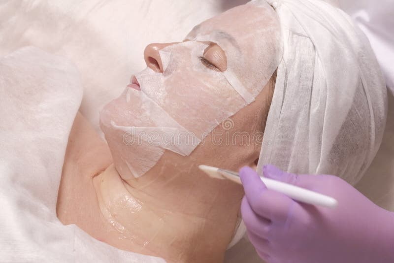 Cosmetología Tratamiento antiedad de la piel La máscara en la cara de la mujer La chica en el salón de belleza en la recepción de fotos de archivo libres de regalías Cosmetología Tratamiento antiedad de la piel La máscara en la cara de la mujer La chica en el salón de belleza en la recepción de fotos de archivo libres de regalías