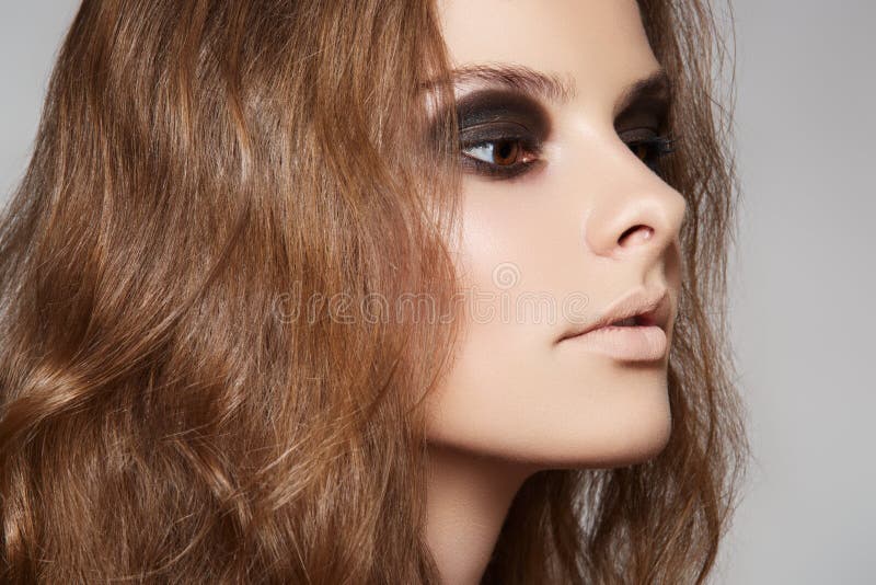 Wellness, cosmetics and haircare. Portrait of woman model with shiny long volume brown hair on gray background. Wellness, cosmetics and haircare. Portrait of woman model with shiny long volume brown hair on gray background