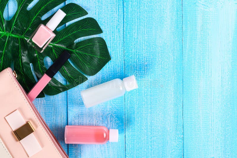 Cosmétiques dans un sac cosmétique rose Lustre de lèvre, crème, vernis à ongles, produits de soin pour la peau sur une feuille tr photographie stock Cosmétiques dans un sac cosmétique rose Lustre de lèvre, crème, vernis à ongles, produits de soin pour la peau sur une feuille tr photographie stock