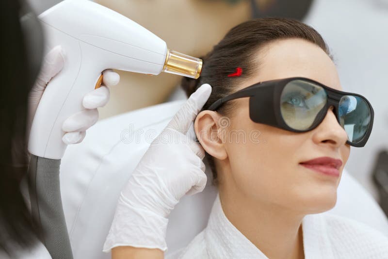 cosmétologie Femme au traitement de stimulation de laser de croissance de cheveux photographie stock libre de droits cosmétologie Femme au traitement de stimulation de laser de croissance de cheveux photographie stock libre de droits