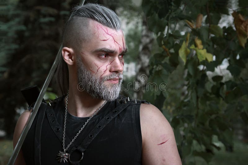 Cosplay, vestido como um herói Geralt de Rivia do jogo o Witcher, um guerreiro fantástico com uma espada em suas mãos fotografia de stock royalty free Cosplay, vestido como um herói Geralt de Rivia do jogo o Witcher, um guerreiro fantástico com uma espada em suas mãos fotografia de stock royalty free