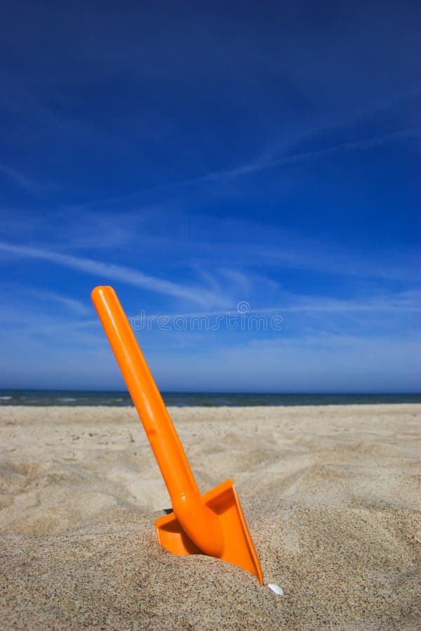 Orange plastic spade in the sandy seashore. Orange plastic spade in the sandy seashore