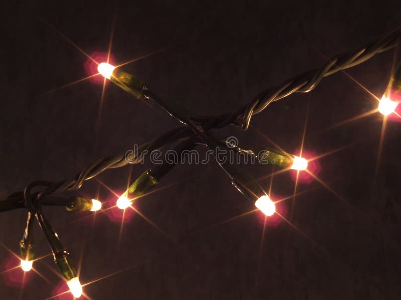 Single strand of lit Christmas lights against a dark background. Lights have a starlight filtered glow. Single strand of lit Christmas lights against a dark background. Lights have a starlight filtered glow.