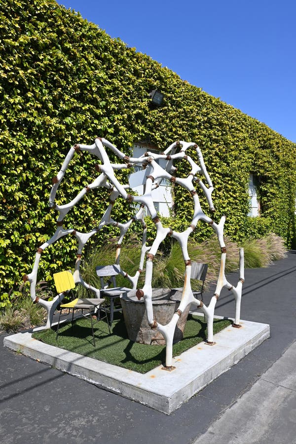 COSTA MESA,CALIFORNIA - 4 APR 2023: Dinosaur skeleton sculpture with table and chairs at The LAB Anti Mall. COSTA MESA,CALIFORNIA - 4 APR 2023: Dinosaur skeleton sculpture with table and chairs at The LAB Anti Mall.