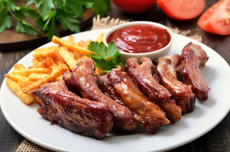 Costole di carne di maiale, fritture della patata e salsa al pomodoro, fine sulla vista fotografia stock Costole di carne di maiale, fritture della patata e salsa al pomodoro, fine sulla vista fotografia stock