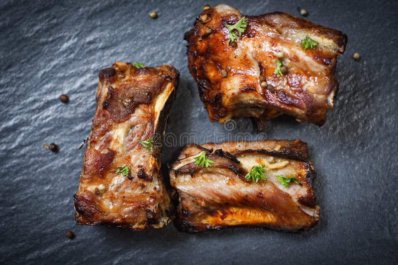 Costole di carne di maiale del Bbq grigliate con le spezie delle erbe servite sul piatto scuro - la costola di maiale di carne di immagini stock libere da diritti Costole di carne di maiale del Bbq grigliate con le spezie delle erbe servite sul piatto scuro - la costola di maiale di carne di immagini stock libere da diritti
