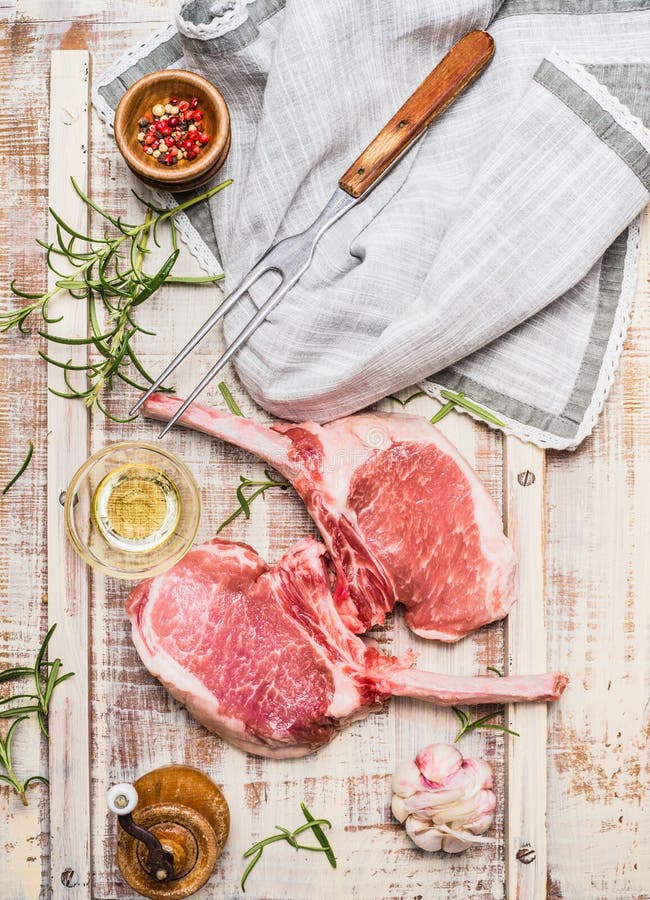 A costoleta gourmet crua da carne de porco para a grade, o BBQ ou o cozimento com ervas, especiarias e carne bifurcam-se no fundo fotografia de stock A costoleta gourmet crua da carne de porco para a grade, o BBQ ou o cozimento com ervas, especiarias e carne bifurcam-se no fundo fotografia de stock