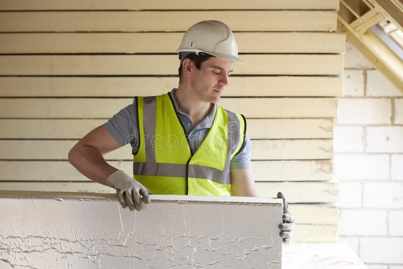 Costruttore Fitting Insulation Boards nel tetto di nuova casa fotografia stock libera da diritti Costruttore Fitting Insulation Boards nel tetto di nuova casa fotografia stock libera da diritti