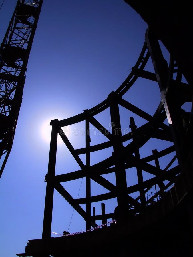 Silhouetted steel structure and support beams of a building under construction. Silhouetted steel structure and support beams of a building under construction.