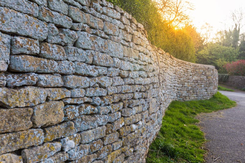 Old traditional Cotswolds stone fence wall shown in leading perspective with sun flare. Old traditional Cotswolds stone fence wall shown in leading perspective with sun flare