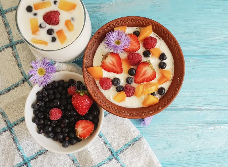 Cottage cheese healthy dessert diet yogurt, strawberry, apricot, blueberry on a blue background, flower. Cottage cheese yogurt, strawberry, apricot, blueberry on royalty free stock image Cottage cheese healthy dessert diet yogurt, strawberry, apricot, blueberry on a blue background, flower. Cottage cheese yogurt, strawberry, apricot, blueberry on royalty free stock image