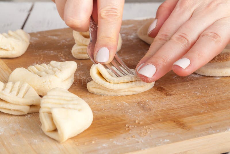 Cottura e concetto domestico - fine su delle mani che producono i biscotti dalla pasta fresca a casa fotografia stock Cottura e concetto domestico - fine su delle mani che producono i biscotti dalla pasta fresca a casa fotografia stock