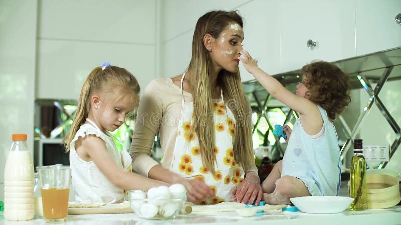 Cottura in famiglia. madre con figlie che prepara il cibo in cucina archivi video