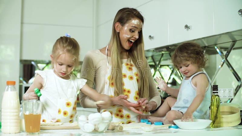 Cottura in famiglia. madre con figlie che prepara il cibo in cucina video d archivio