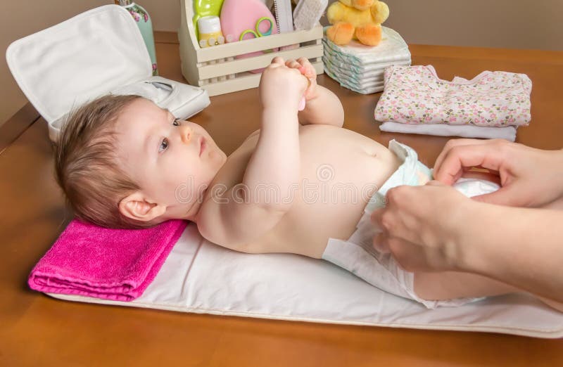Couche-culotte changeante de mère de bébé adorable photographie stock libre de droits Couche-culotte changeante de mère de bébé adorable photographie stock libre de droits