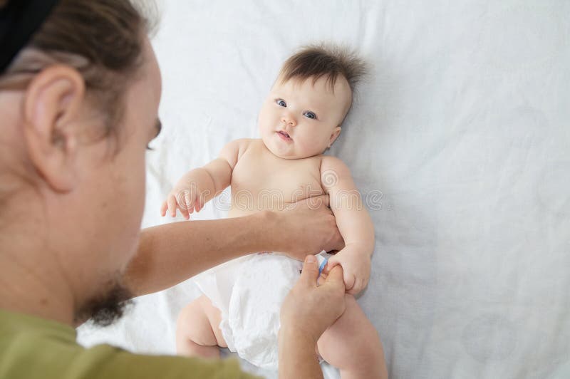 Couche-culotte changeante de papa sur le bébé sur le lit, couche changeante, vie quotidienne photo stock Couche-culotte changeante de papa sur le bébé sur le lit, couche changeante, vie quotidienne photo stock