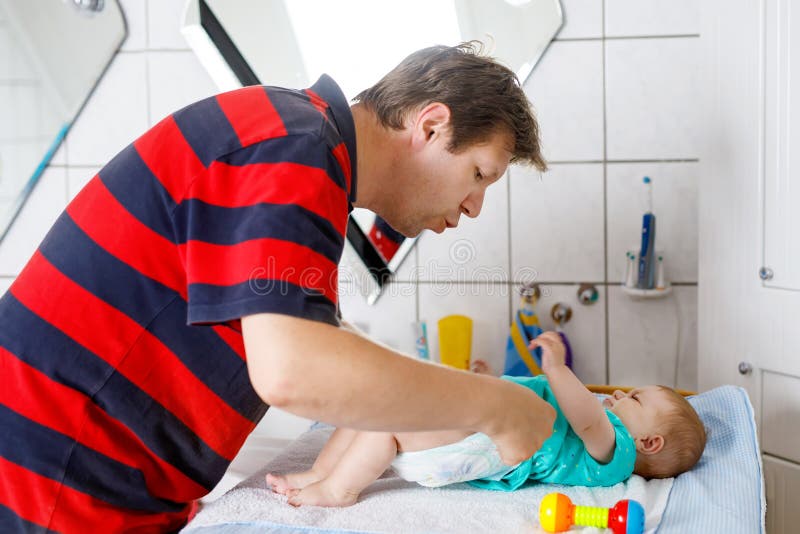 Couche-culotte changeante de père affectueux de sa fille nouveau-née de bébé images libres de droits Couche-culotte changeante de père affectueux de sa fille nouveau-née de bébé images libres de droits
