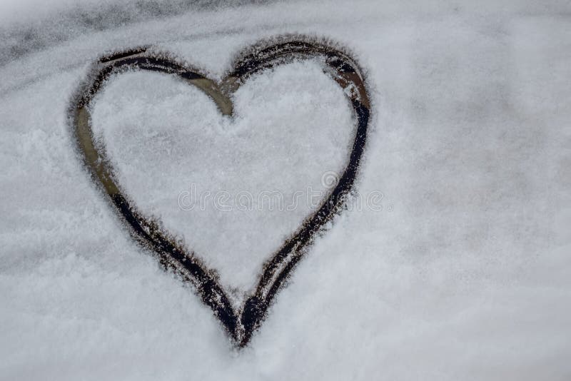 Smooth layer of snow on the side window of a car. On which the heart is drawn. Close-up. Winter. Relationship concept. Smooth layer of snow on the side window of a car. On which the heart is drawn. Close-up. Winter. Relationship concept