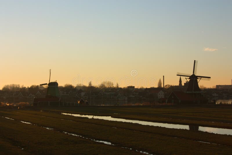 Coucher de soleil romantique aux couleurs rouge et jaune la plaine de la campagne rurale de zaanse schans avec ses moulins typiqu image libre de droits Coucher de soleil romantique aux couleurs rouge et jaune la plaine de la campagne rurale de zaanse schans avec ses moulins typiqu image libre de droits