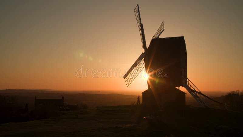 Coucher de soleil à l'horizon derrière un moulin traditionnel en bois au coucher du soleil avec des personnes anonymes marchant un