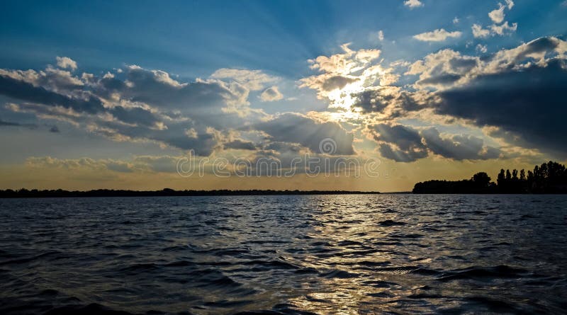 Coucher du soleil chaud d'été au-dessus de la rivière Danube sur le fond d'un ciel bleu photos libres de droits Coucher du soleil chaud d'été au-dessus de la rivière Danube sur le fond d'un ciel bleu photos libres de droits