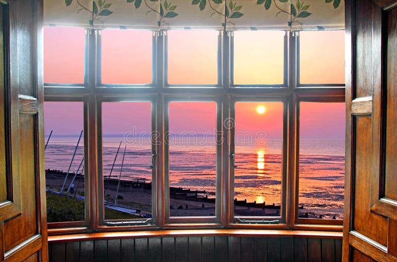 Photo of a beautiful georgian window bay overlooking a lovely golden sunset by the coast. Photo of a beautiful georgian window bay overlooking a lovely golden sunset by the coast.