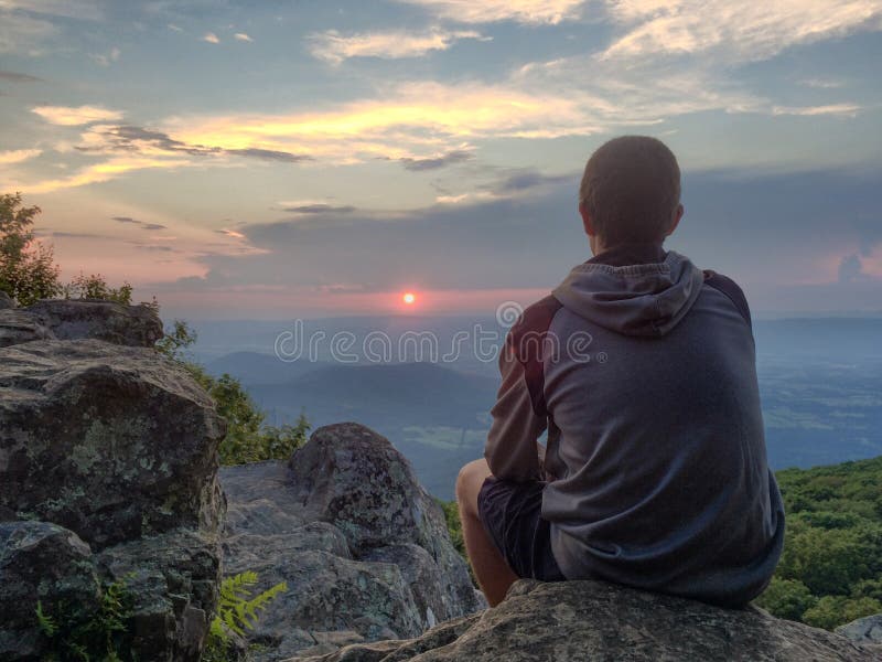 Coucher du soleil de observation de jeune homme à partir de dessus de montagne en parc national de Shenandoah photo stock Coucher du soleil de observation de jeune homme à partir de dessus de montagne en parc national de Shenandoah photo stock