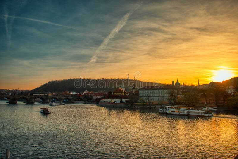 Coucher du soleil de Prague par la rivière de Vltava avec la lumière chaude de bateaux photo libre de droits Coucher du soleil de Prague par la rivière de Vltava avec la lumière chaude de bateaux photo libre de droits