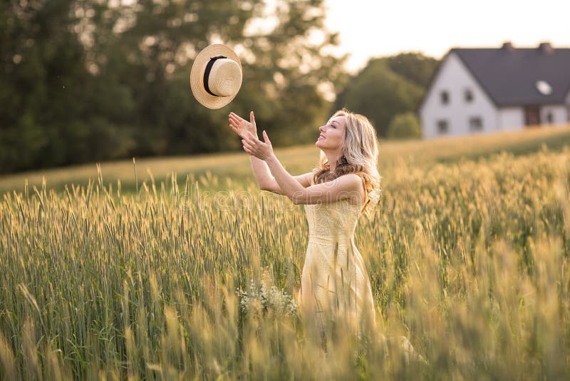 Coucher du soleil en ?t? Dur?e rurale Une jeune femme dans le domaine jette un chapeau images stock Coucher du soleil en ?t? Dur?e rurale Une jeune femme dans le domaine jette un chapeau images stock