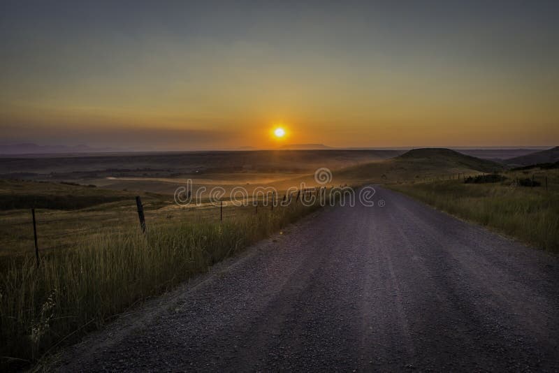 Dusty dirt road with a red sunset in rural America. Dusty dirt road with a red sunset in rural America