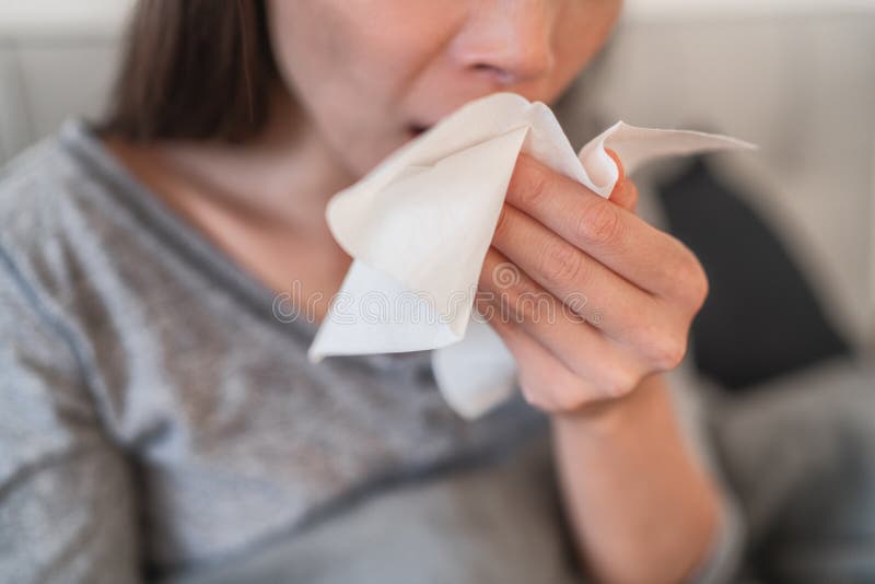 Cough in tissue covering nose and mouth when coughing as COVID-19 hygiene guidelines for coronavirus spread prevention