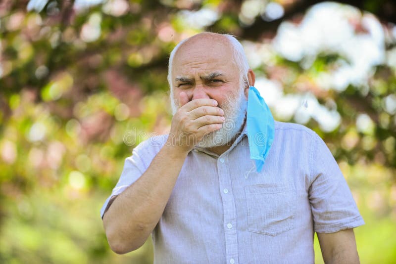 Coughing man in respirator mask. spring blossom tree in park. coronavirus covid19. spring enjoyment. restricted public royalty free stock image Coughing man in respirator mask. spring blossom tree in park. coronavirus covid19. spring enjoyment. restricted public royalty free stock image