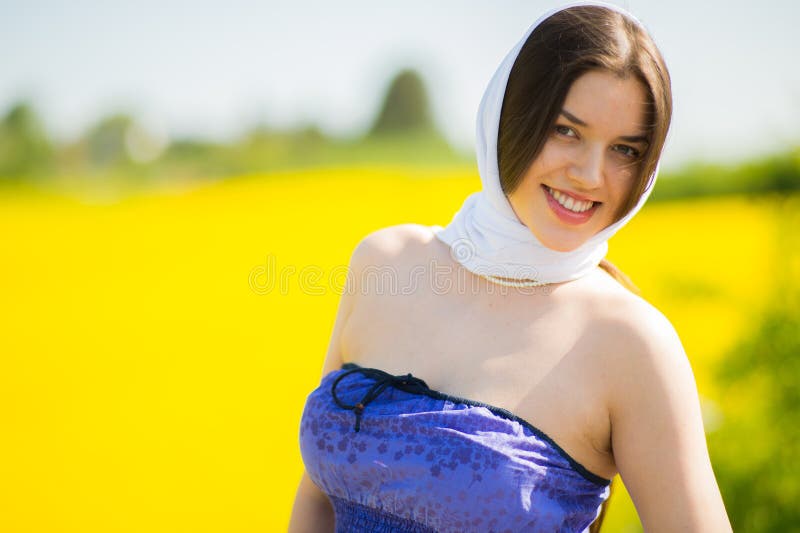 Country girl in a good mood walks in a rape field in summer