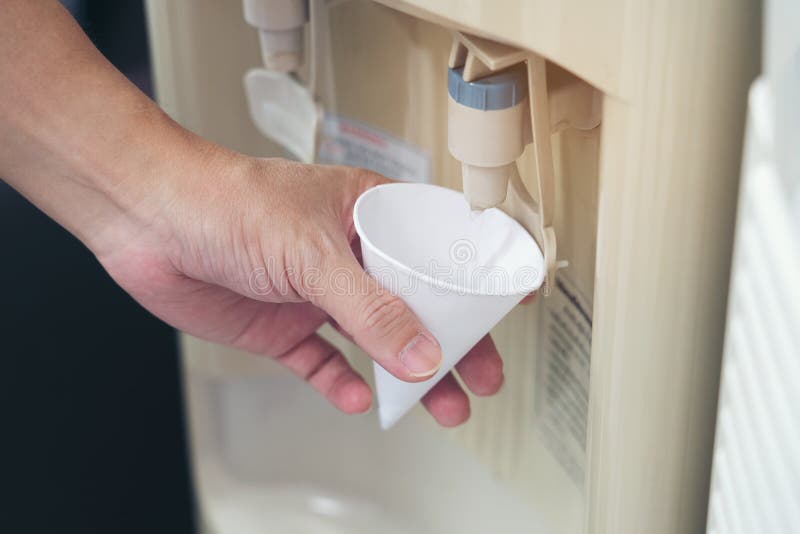 Coupe de papier à main pour l'eau potable à partir d'un distributeur d'eau froide ou chaude La main rapprochée d'une femelle vers. Coupe de papier à main pour l'eau potable à partir d'un distributeur d'eau froide ou chaude La main rapprochée des femmes cale de l'eau froide avec un distributeur de refroidisseurs , Health Care and Houhold Concept ok