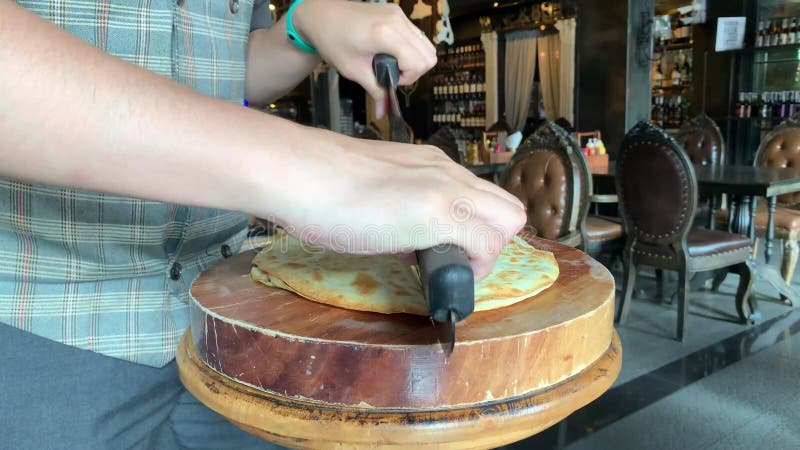 Couper une pizza de style mexicain fraîchement cuite en plusieurs tranches avec un couteau semi-circulaire. journée nationale de l banque de vidéos