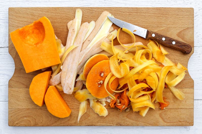 Coupez la courge de butternut avec les peaux et le couteau sur le chopp en bois brun photo stock Coupez la courge de butternut avec les peaux et le couteau sur le chopp en bois brun photo stock