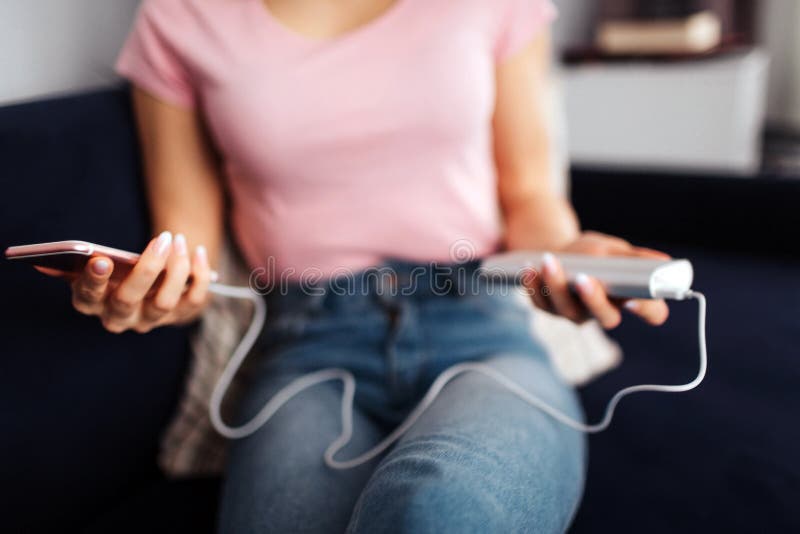 Coupez la vue du téléphone de prise de jeune femme avec la charge branchée dans à elle Elle les tiennent des deux mains Le modèle image libre de droits Coupez la vue du téléphone de prise de jeune femme avec la charge branchée dans à elle Elle les tiennent des deux mains Le modèle image libre de droits