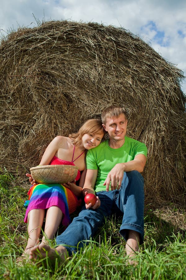 Couple with apples sitting on the grass hay royalty free stock photos