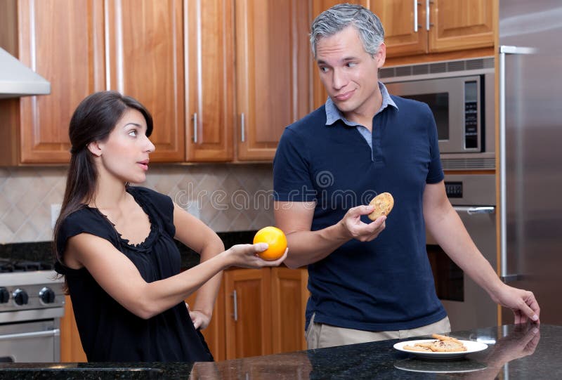 a young attractive couple arguing over junk food and healthy diets and nutrition. a young attractive couple arguing over junk food and healthy diets and nutrition