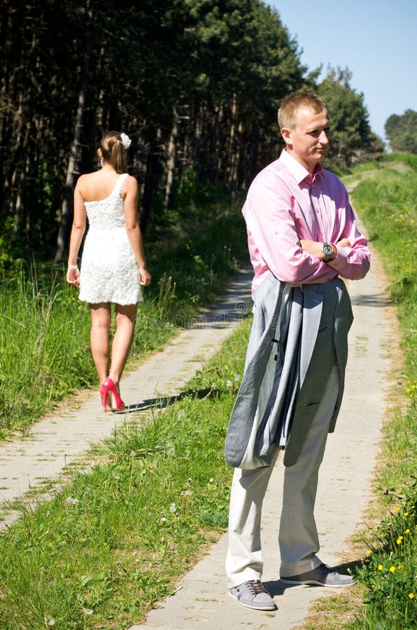 Couple arguing during a walk in the countryside with the fashionable woman walking away.