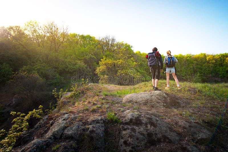 Couple of backpackers or hikers stands on mountain top at sunset stock photos Couple of backpackers or hikers stands on mountain top at sunset stock photos