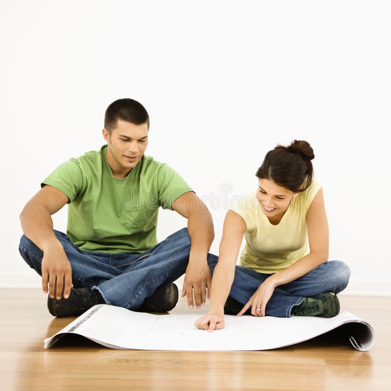 Attractive young adult couple looking at house plans. Attractive young adult couple looking at house plans.