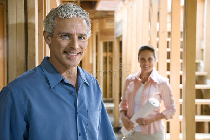 Happy couple smile at the camera inside their partially constructed home. Horizontal shot. Happy couple smile at the camera inside their partially constructed home. Horizontal shot.