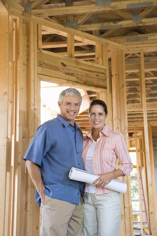 Happy couple stand together inside their home under construction. Vertical shot. Happy couple stand together inside their home under construction. Vertical shot.