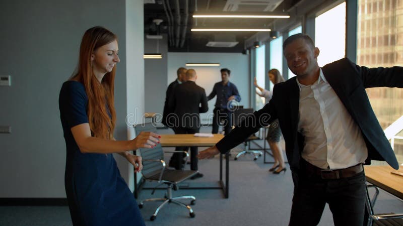 Couple in business office dancing after winning deal celebrating