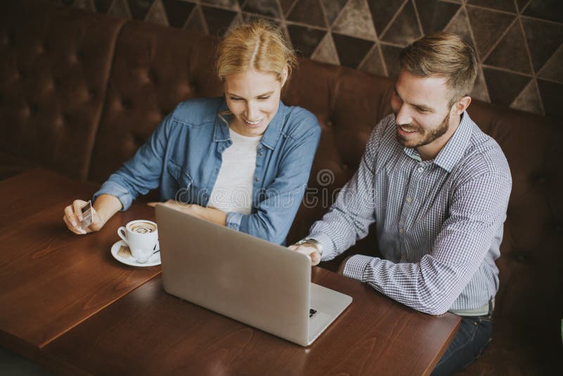 Couple buying online with credit card and laptop in a coffee sho stock photos Couple buying online with credit card and laptop in a coffee sho stock photos